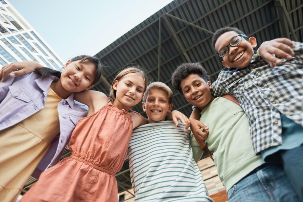 A mixed gender group of young people wearing brightly colored clothes smiling into the camera.