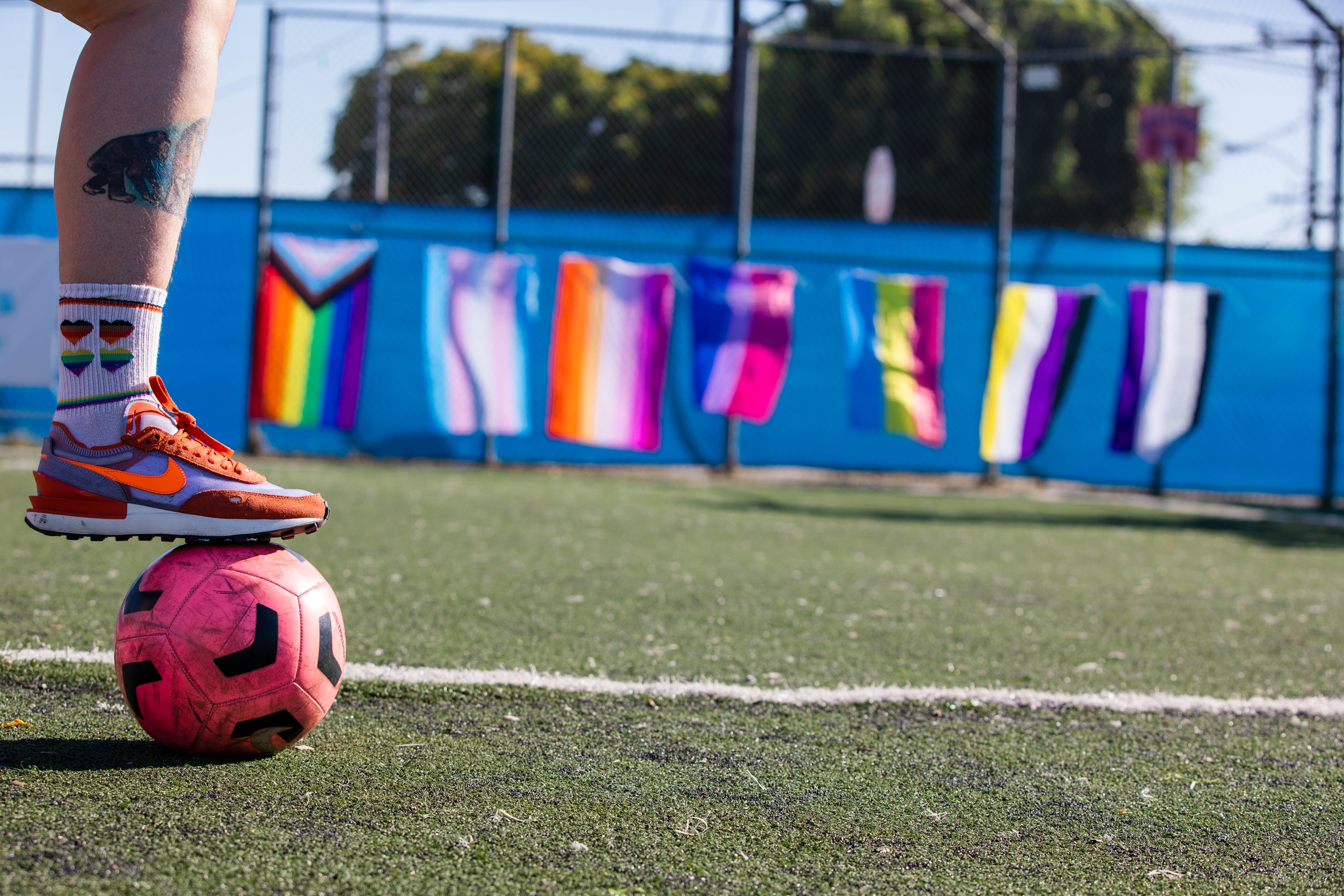 A person's foot balancing on top of a football, in a field.