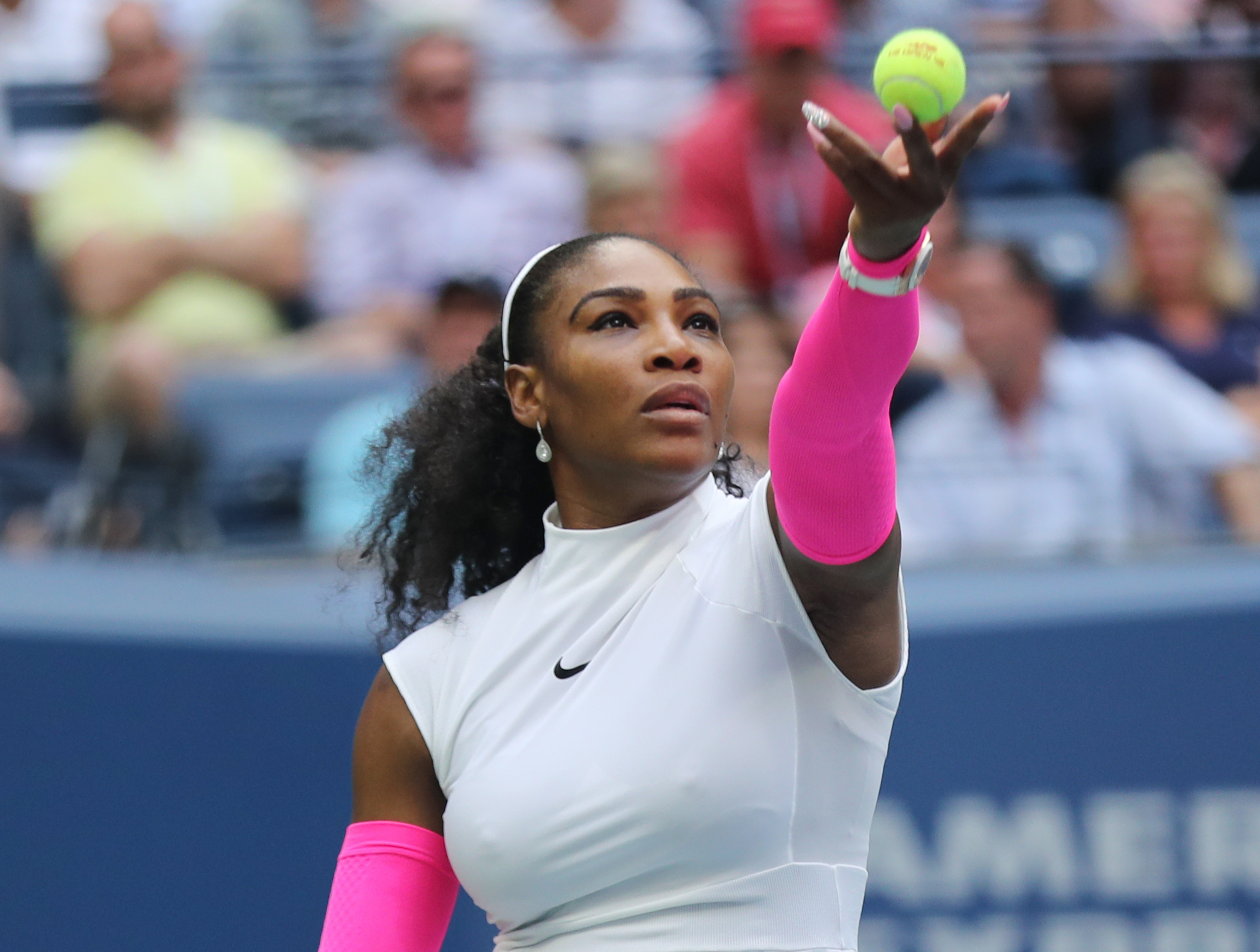 Serena throwing a ball up in the air to serve